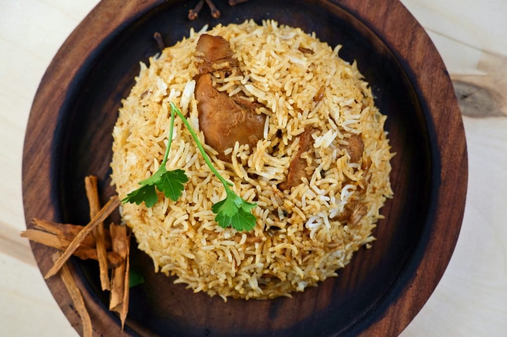 Indian traditional dish with rice and coriander leaf on wooden tray