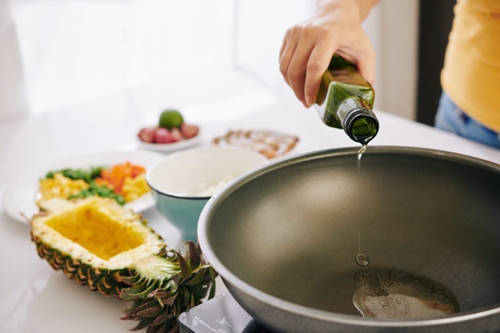 Woman pouring oil in frying pan