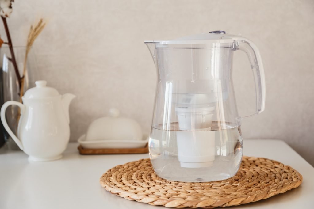 Glass and jug with fresh water on table in the kintchen