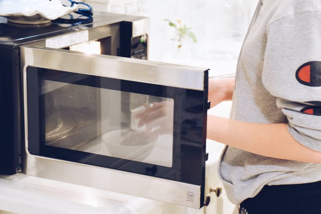 Teenage girl using microwave oven in a kitchen at home