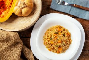 Pumpkin risotto, recipe with rice and pumpkin on rustic table with ingredients.