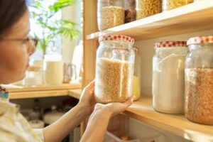 Food storage in pantry, woman holding jar of rice in hand