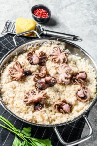 Italian Risotto with octopus and mushrooms. Gray background. Top view