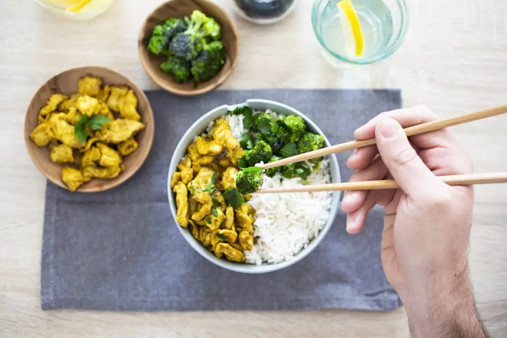 Curry chicken, broccoli and rice, man holding chopsticks with broccoli