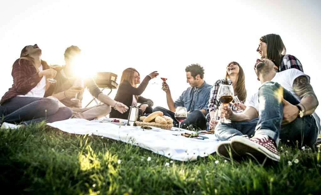 Group of friends having fun while eating and drinking at a pic-nic - Happy people at bbq party